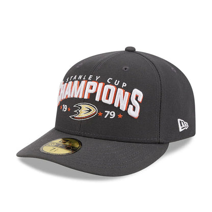 Anaheim Ducks NHL Stanley Cup Champions Dark Grey New Era 59FIFTY Fitted Cap, three-quarter view showing raised white and orange embroidered CHAMPIONS lettering on the front panel, with a gold Anaheim Ducks logo.