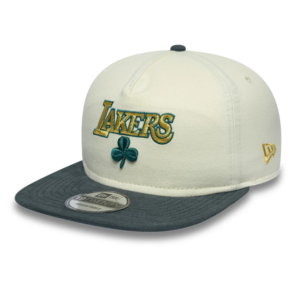 LA Lakers NBA Metallic Logo Cream New Era 19TWENTY Adjustable Cap, three-quarter view showing the gold Lakers logo and green clover on the front panel, dark grey flat visor with a 19TWENTY size sticker, and gold New Era flag logo on the left side.