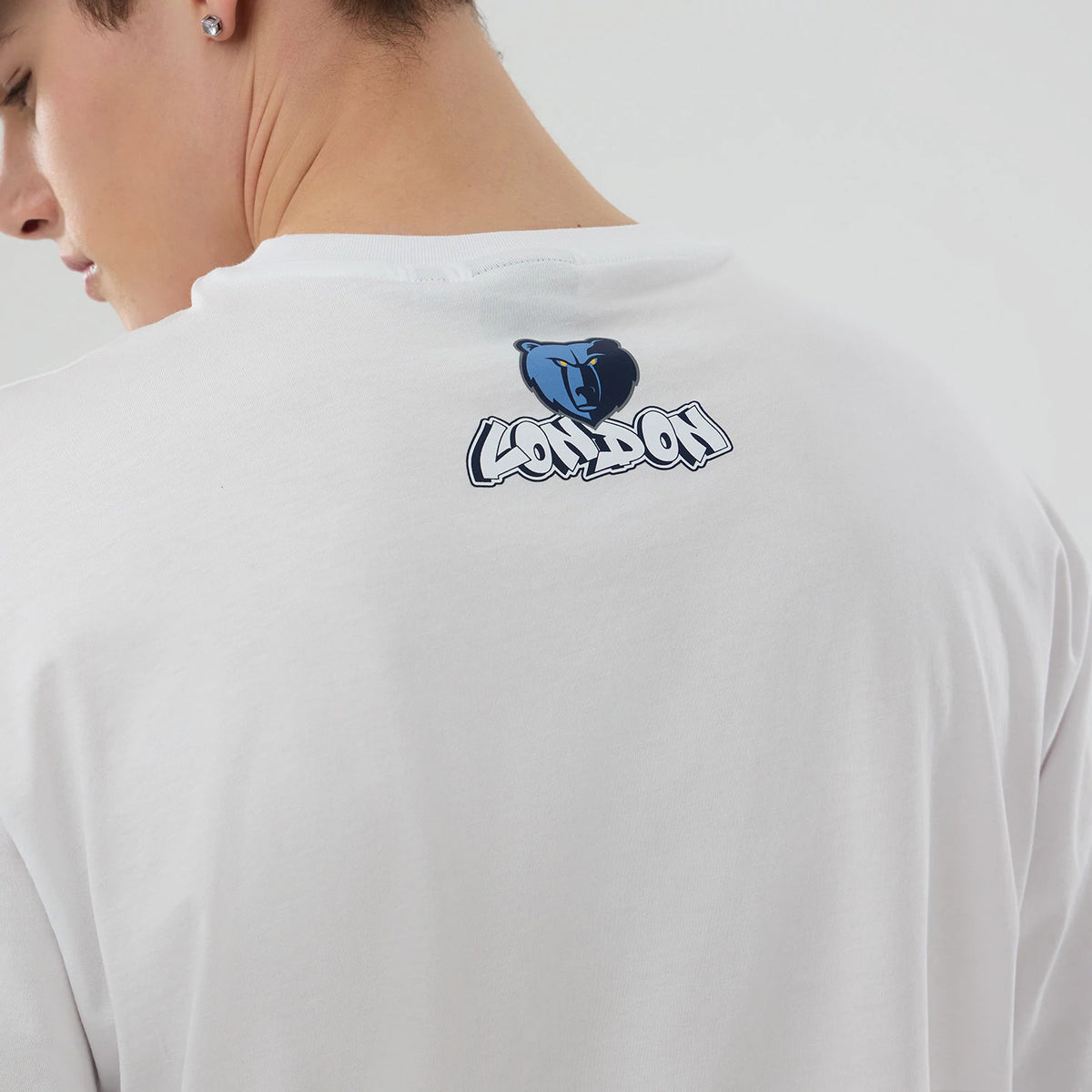 New Era Memphis Grizzlies NBA London Game 2026 White Oversized T-Shirt, back view on a model displaying a printed blue bear logo above stylised 'London' lettering at the centre near the neckline, showing the soft drape of the white fabric.