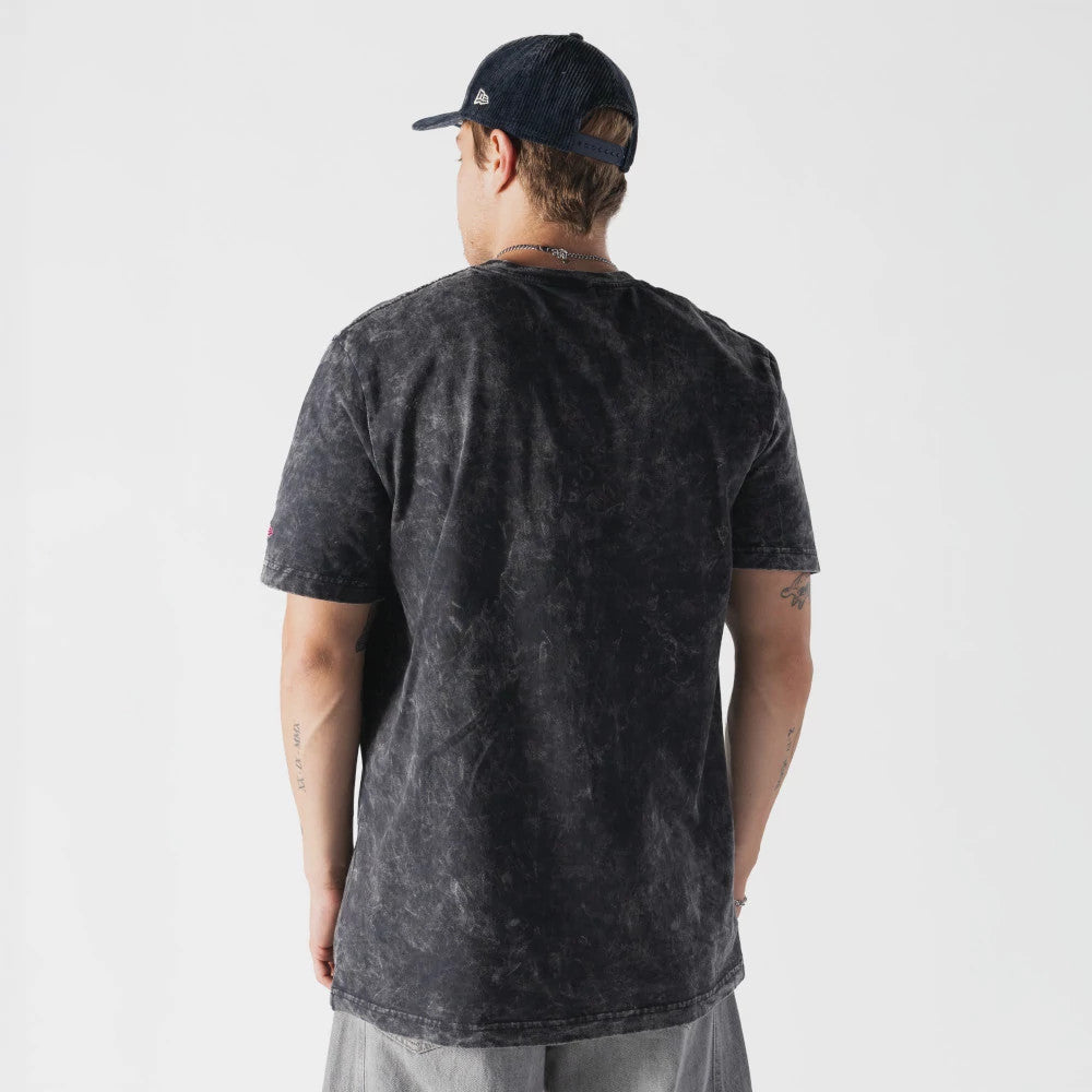 New Era Netflix Stranger Things Hell Fire Club Black T-Shirt, back view on a model wearing a dark cap, showing a marbled texture across the shirt's black fabric, with short sleeves and a straight hem falling over light trousers.