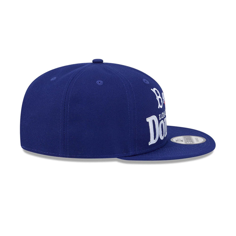 LA Dodgers MLB Cooperstown Throwback Blue New Era 9FIFTY Snapback Adjustable Cap, side view showing the prominent white raised embroidery of the team name on the structured blue crown, with a flat blue visor and a 9FIFTY size sticker.