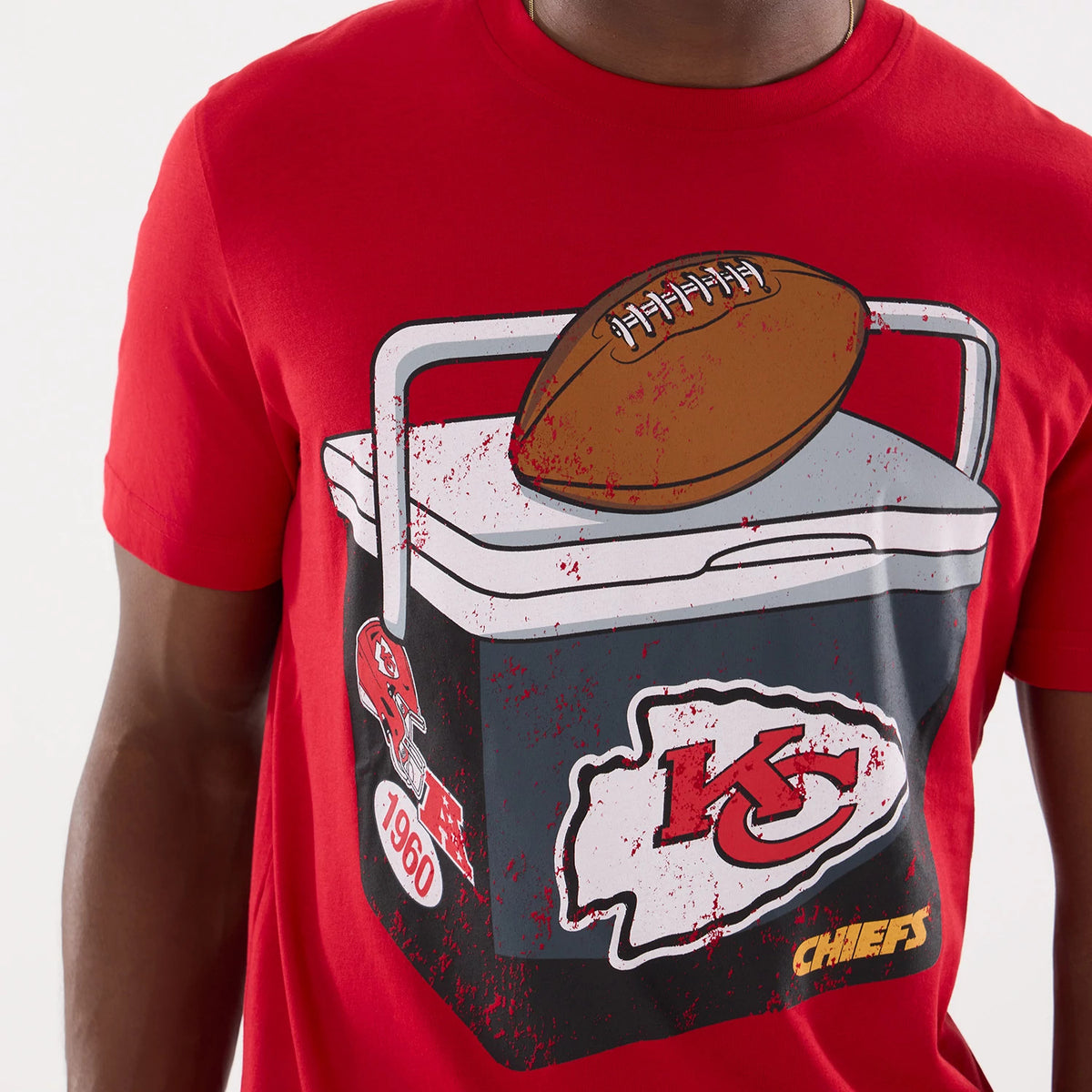 New Era Kansas City Chiefs NFL Training 2026 Red T-Shirt, front view on-model displaying a graphic of a cooler with a brown football on top, featuring the Kansas City Chiefs logo prominently adorned on the front, with Chiefs lettering below.