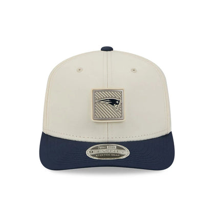 Patriots NFL Training 2026 White New Era 9SEVENTY Stretch Snap Adjustable Cap, front view showing a large square Patriots logo patch on the structured white crown, with a contrast navy visor and a 9SEVENTY size sticker on the curved visor.