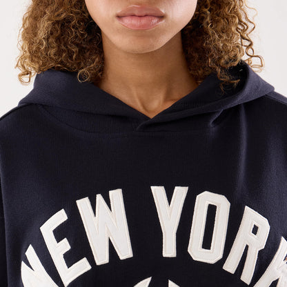New Era New York Yankees Womens MLB Navy Oversized Pullover Hoodie, front view on-model featuring large white embroidered lettering spelling New York across the chest, with a dark navy colour and a relaxed hood draped casually.