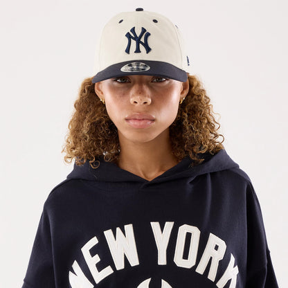 New Era New York Yankees Womens MLB Navy Oversized Pullover Hoodie, front view on a model wearing a matching cap, showing New York lettering across the chest in white, with a spacious hood draped over the shoulders.