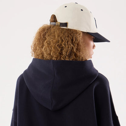 New Era New York Yankees Womens MLB Navy Oversized Pullover Hoodie, back view on-model showing the large hood and relaxed silhouette, paired with a black and white cap featuring an embroidered New Era logo on the strap and eyelets on top.