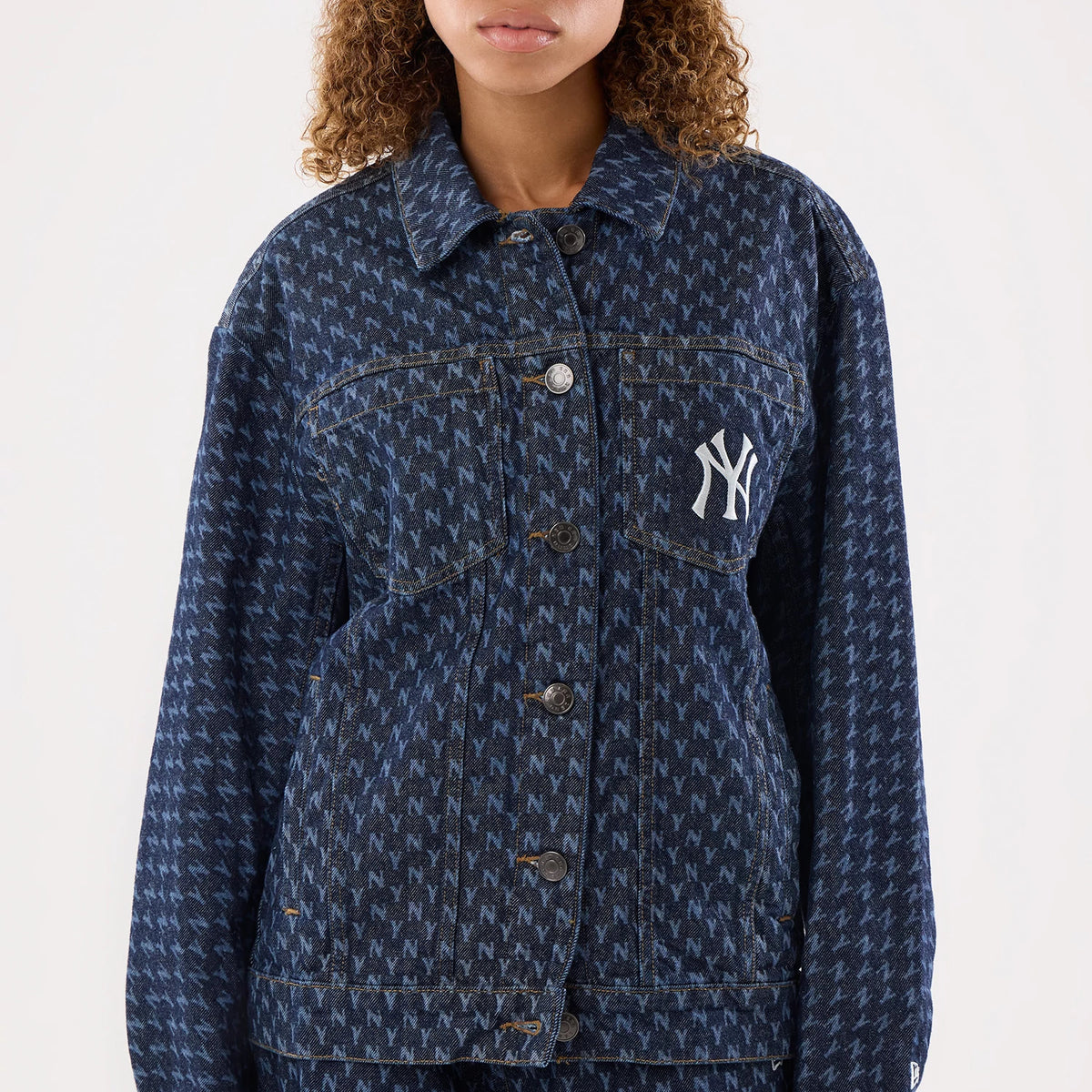 New Era New York Yankees Womens MLB Denim Navy Jacket, front view showing an all-over pattern of white N logos contrasted against the denim navy fabric, with a prominent embroidered NY logo on the left chest and a button-down closure.