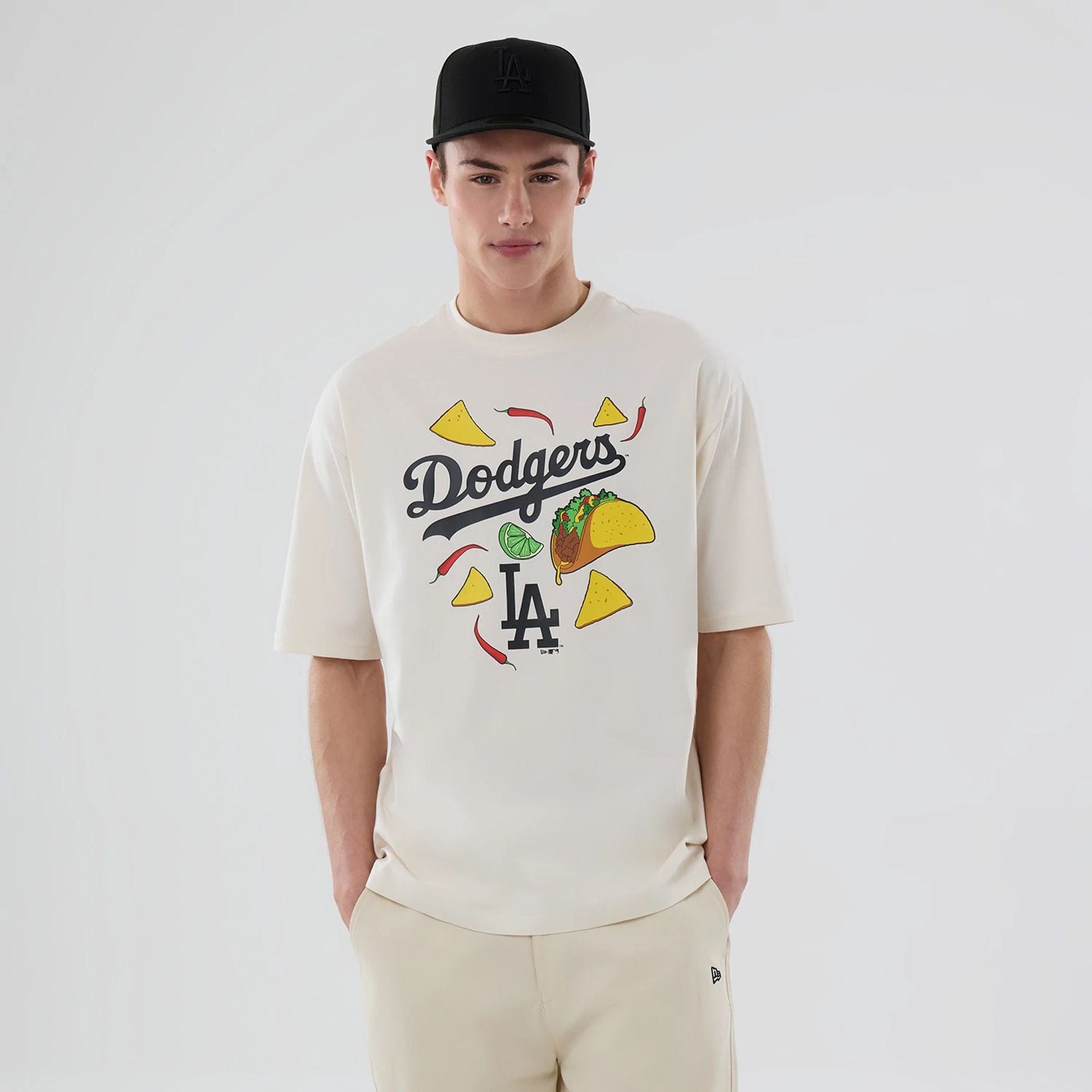 The model is wearing this MLB Food Graphic LA Dodgers Oversized T-Shirt in open white. 1