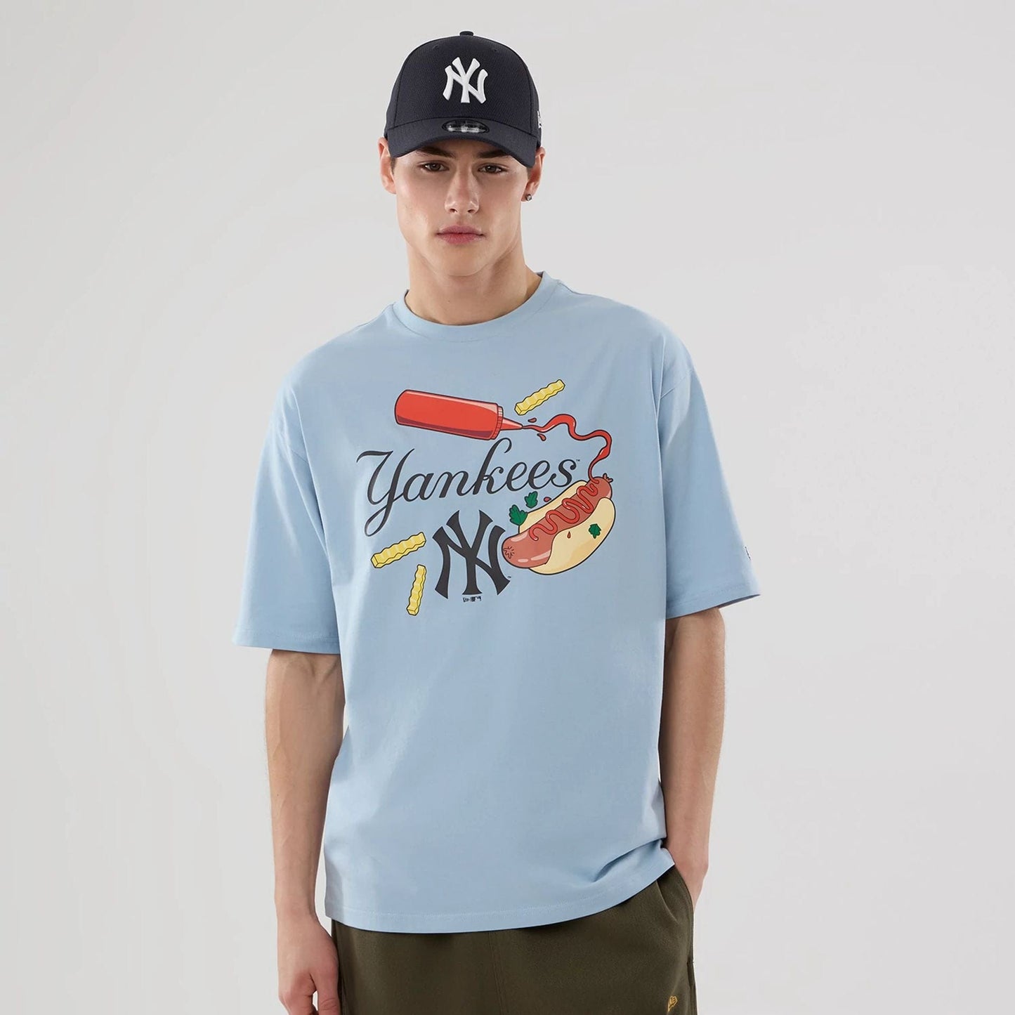 The model is wearing this MLB Food Graphic New York Yankees Oversized T-Shirt in pastel blue. 1