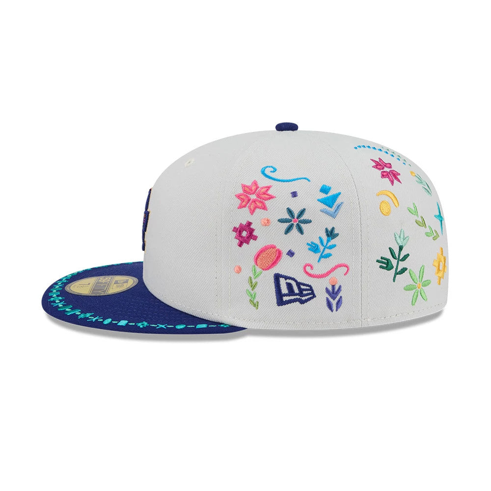 LA Dodgers MLB Heritage Light Beige New Era 59FIFTY Fitted Cap, side view showing multicoloured floral embroidery across the light beige crown, with a navy visor featuring a decorative turquoise pattern and gold 59FIFTY size sticker.