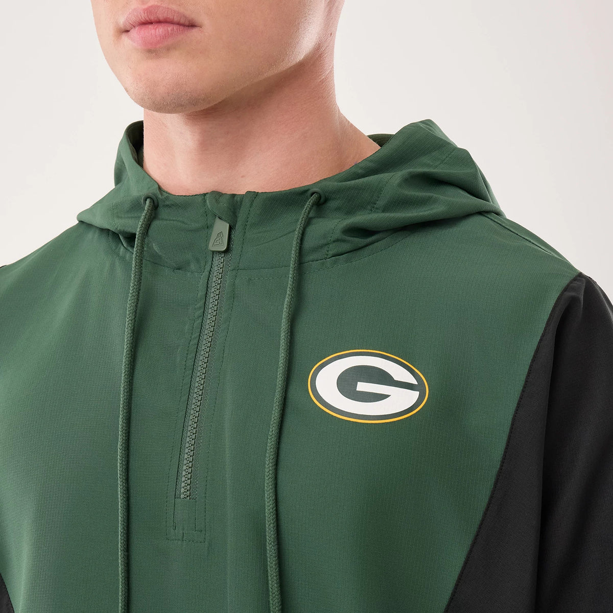 New Era Green Bay Packers NFL Dark Green Jacket, front view on-model showing the embroidered team logo on the left chest, a zip running down from the collar, and a drawstring hood with matching dark green strings and black side panels.