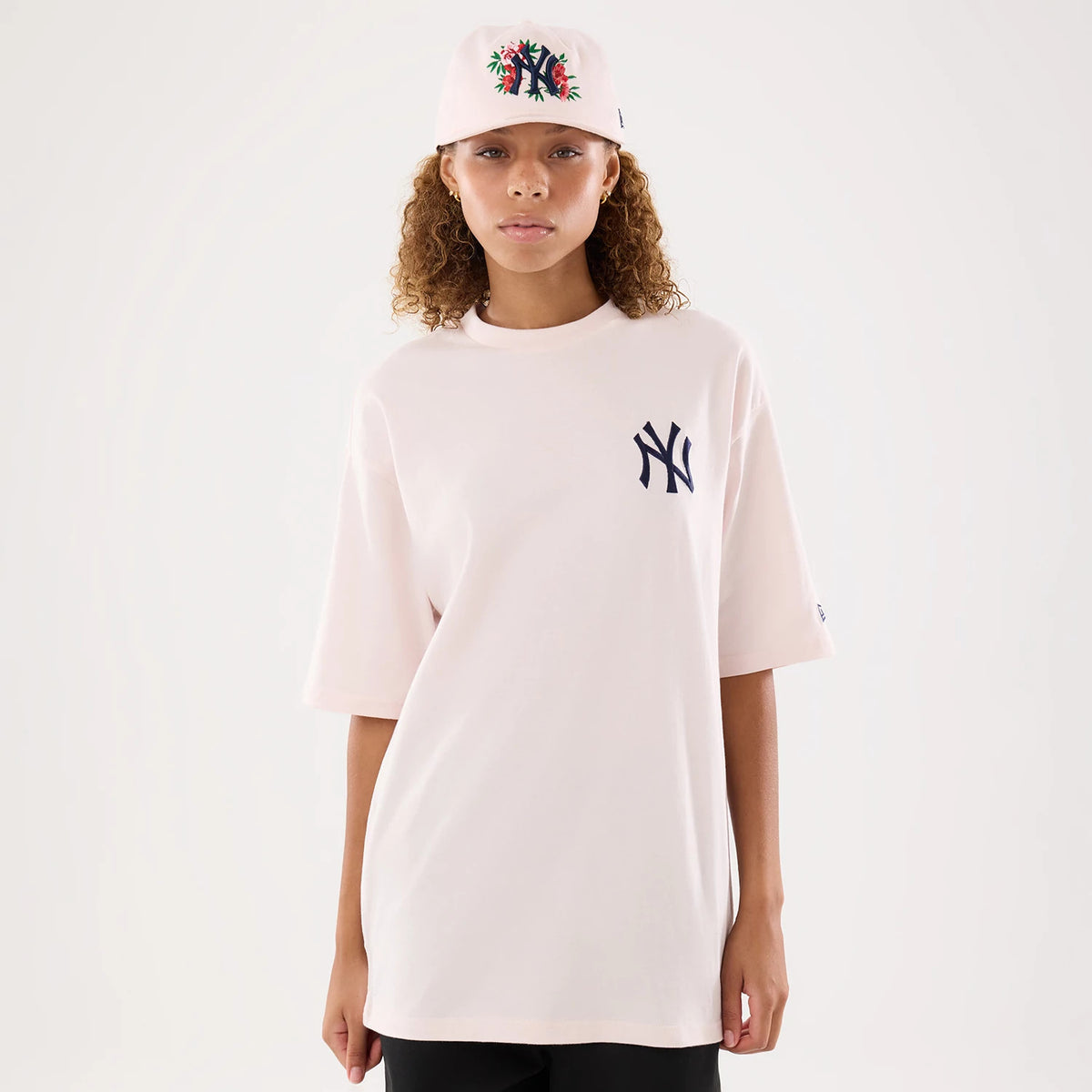 The model is wearing this Womens MLB Graphic New York Yankees T-Shirt in pastel pink. 1