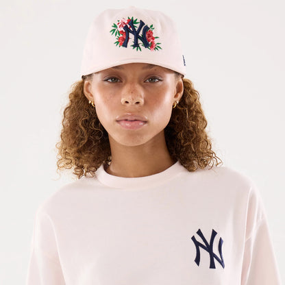 New Era New York Yankees Womens MLB Graphic Pastel Pink T-Shirt, on-model view highlighting the embroidered NY logo on the left chest, complemented by a matching pastel pink cap featuring an embroidered NY logo with floral on the front.
