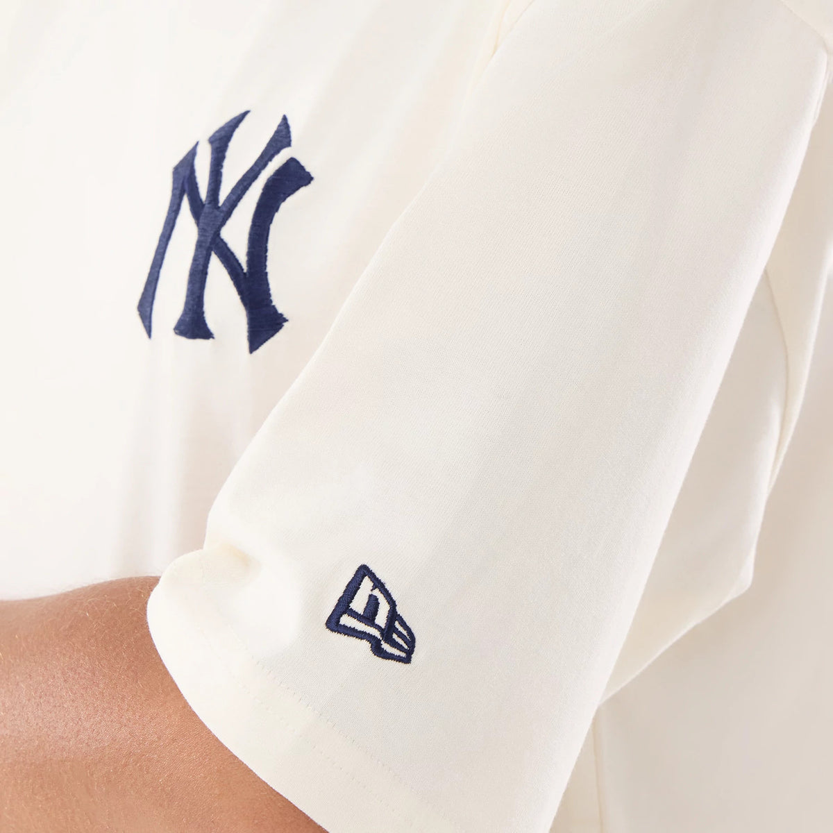 New Era New York Yankees Womens MLB Graphic Open Cream T-Shirt, close-up side view showing the navy embroidered New York Yankees logo on the chest area and a smaller embroidered New Era logo on the sleeve.