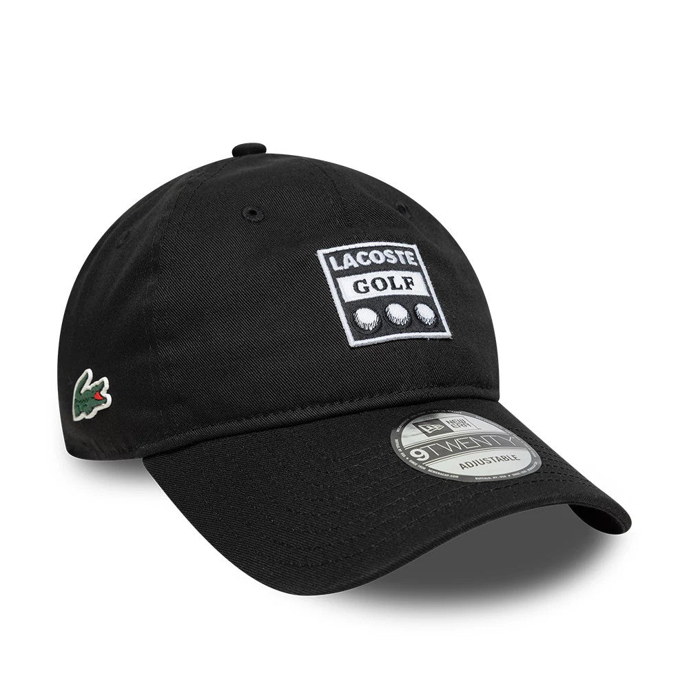 Lacoste X New Era Black 9TWENTY Adjustable Cap, three-quarter view showing the embroidered Lacoste Golf logo on the front panel, a green crocodile patch on the left side, and a 9TWENTY size sticker on the curved black visor.