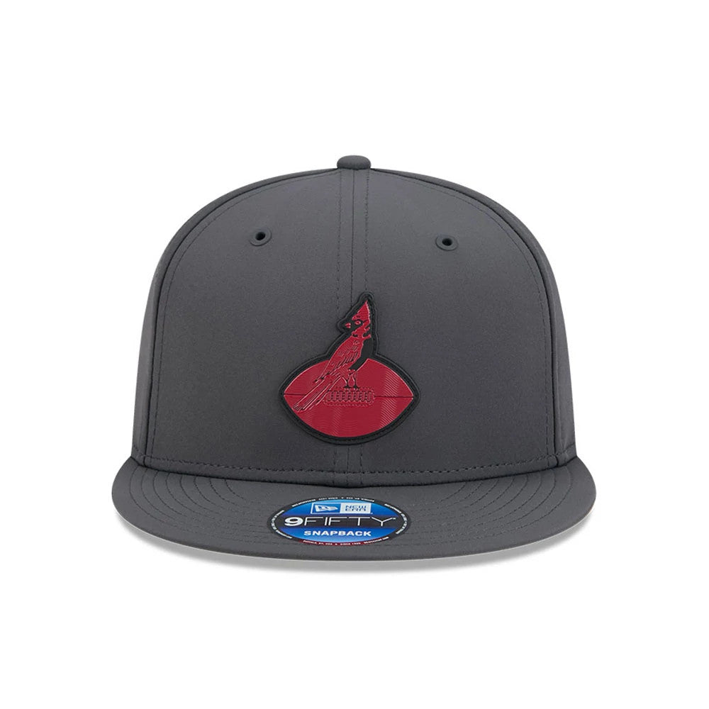 Cardinals NFL Sideline 2026 Charcoal New Era 9FIFTY Snapback Adjustable Cap, front view showing a raised red Cardinals logo on the structured charcoal crown, with charcoal visor and a blue 9FIFTY size sticker centred on the visor.