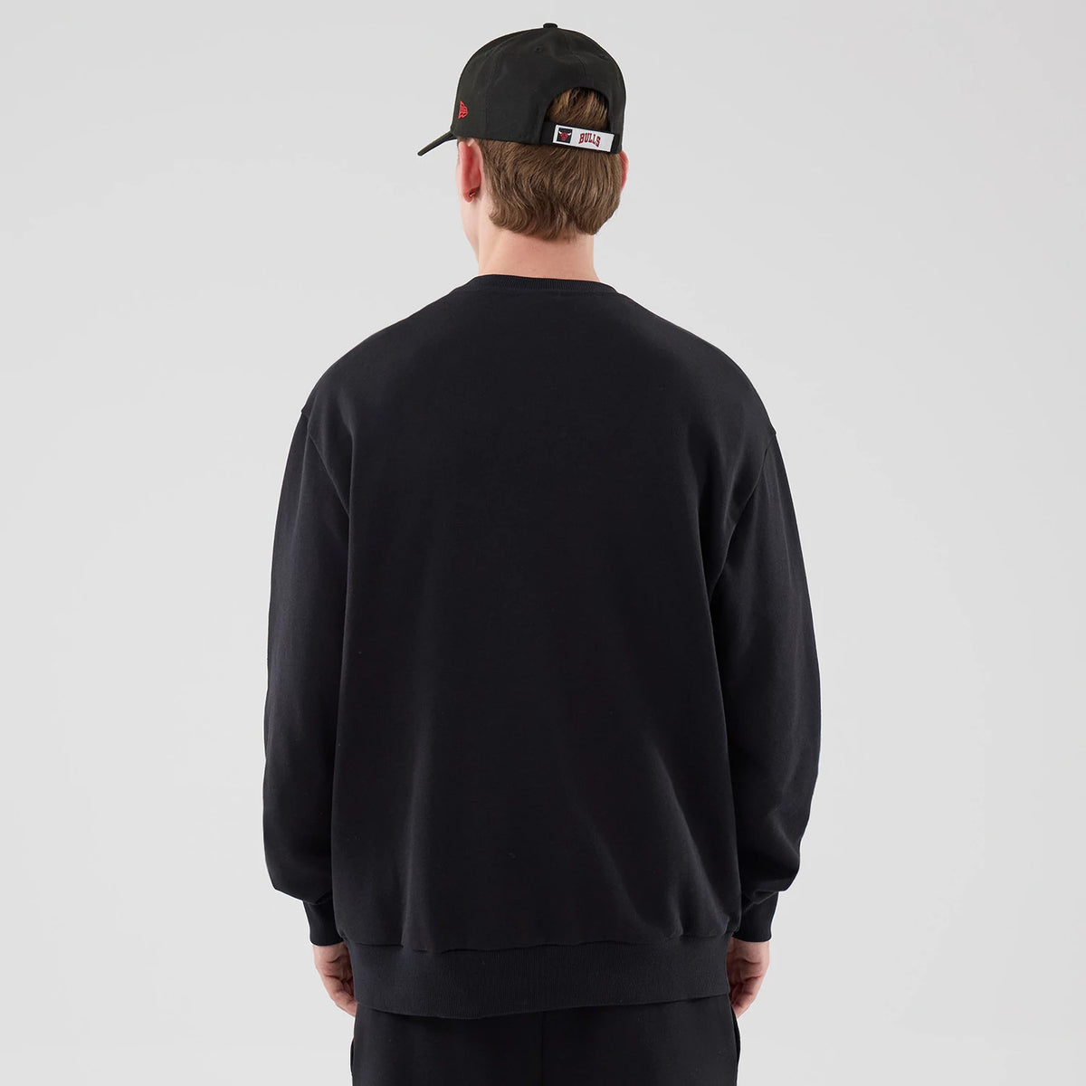 The model is wearing this NBA League Essential Chicago Bulls Oversized Crew Neck Sweater in black. 2