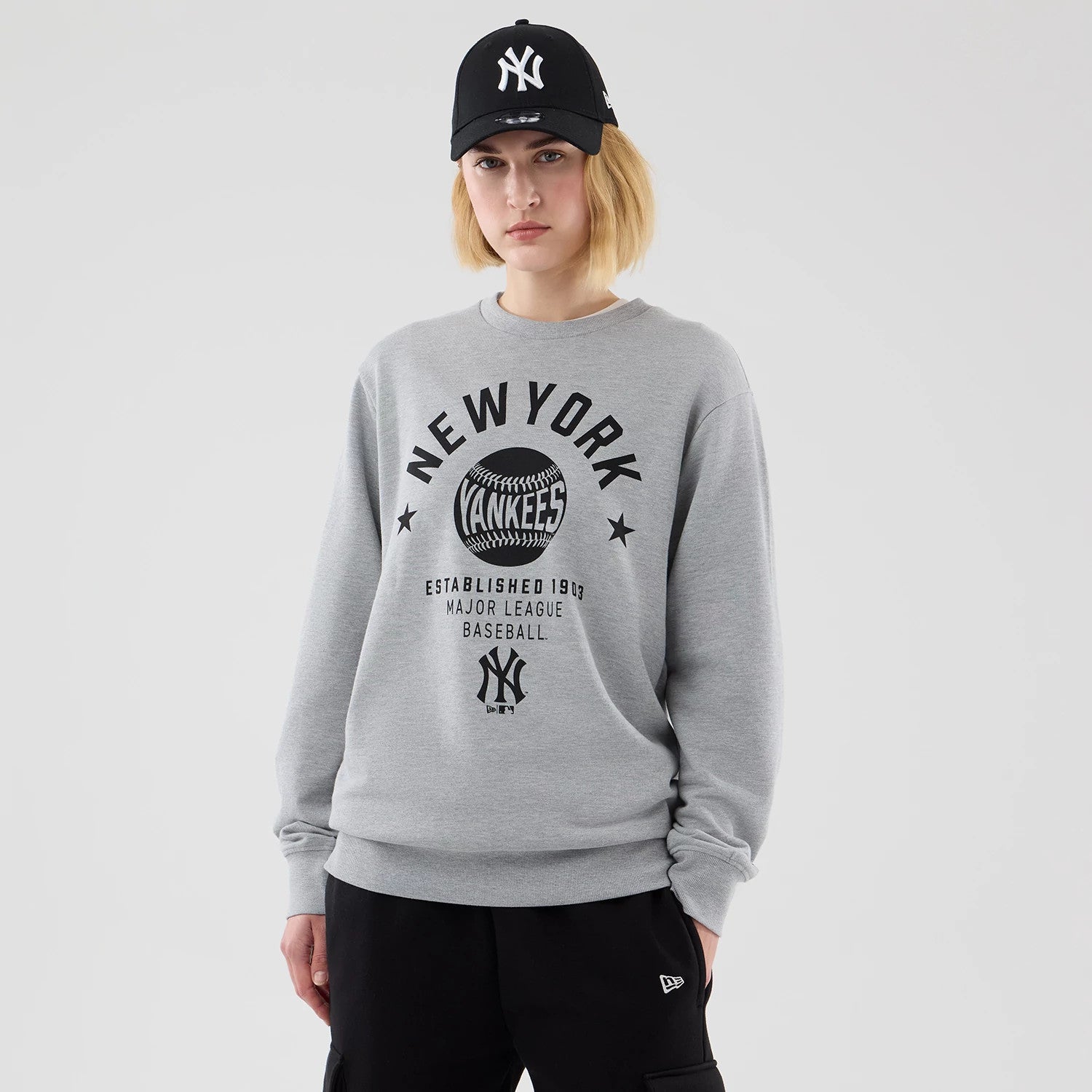 The model is wearing this MLB Graphic New York Yankees Oversized Crew Neck Sweater in grey. 4