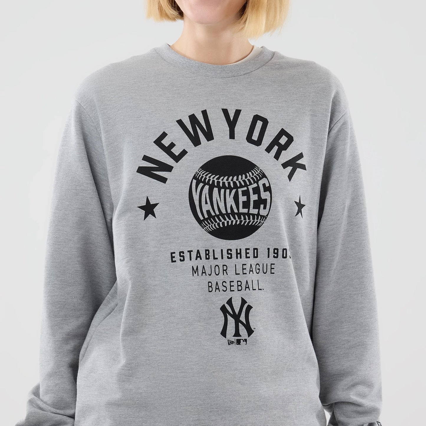 The model is wearing this MLB Graphic New York Yankees Oversized Crew Neck Sweater in grey. 7