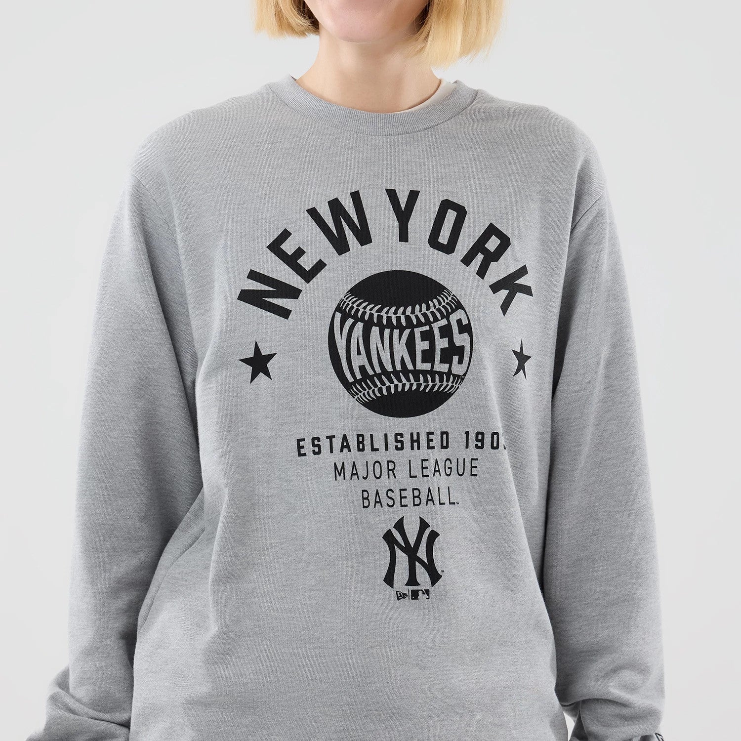 The model is wearing this MLB Graphic New York Yankees Oversized Crew Neck Sweater in grey. 7