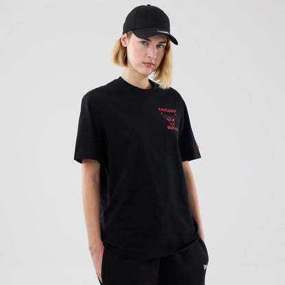 New Era Chicago Bulls NBA Court Graphic Black T-Shirt, front view on-model showing the black short-sleeved tee with a red printed Chicago Bulls logo and text on the left chest, paired with black trousers and a black cap.
