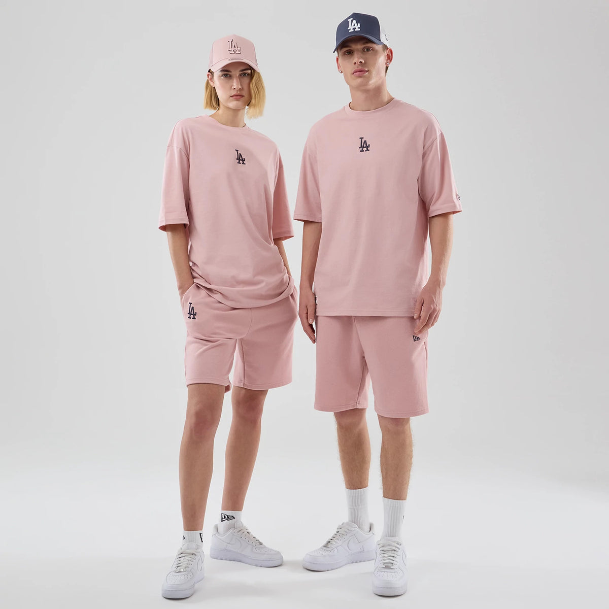 New Era LA Dodgers MLB Midi League Essential Pastel Pink Oversized T-Shirt, front view on-model highlighting the relaxed fit with embroidered LA logo on the chest, styled with matching pastel pink shorts and caps for a coordinated look.