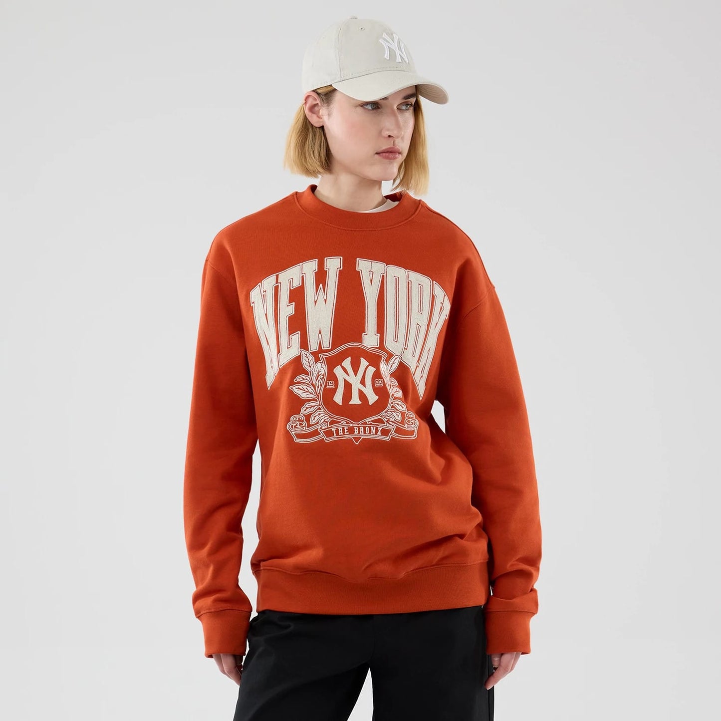 The model is wearing this MLB Arch Graphic New York Yankees Oversized Crew Neck Sweater in Orange. 4