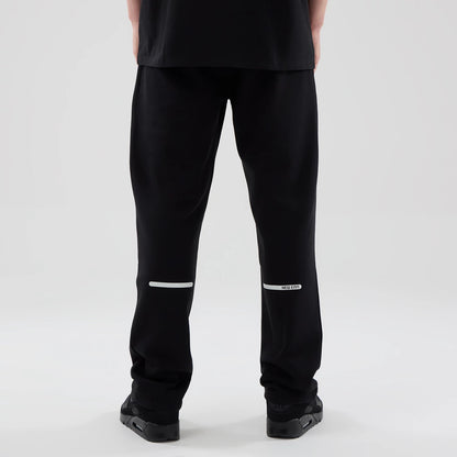 New Era Tech Reflective Black Straight Leg Joggers, back view on a model showing reflective white stripe across the lower legs, with a New Era logo on the right, and a loose fit design around the ankles.