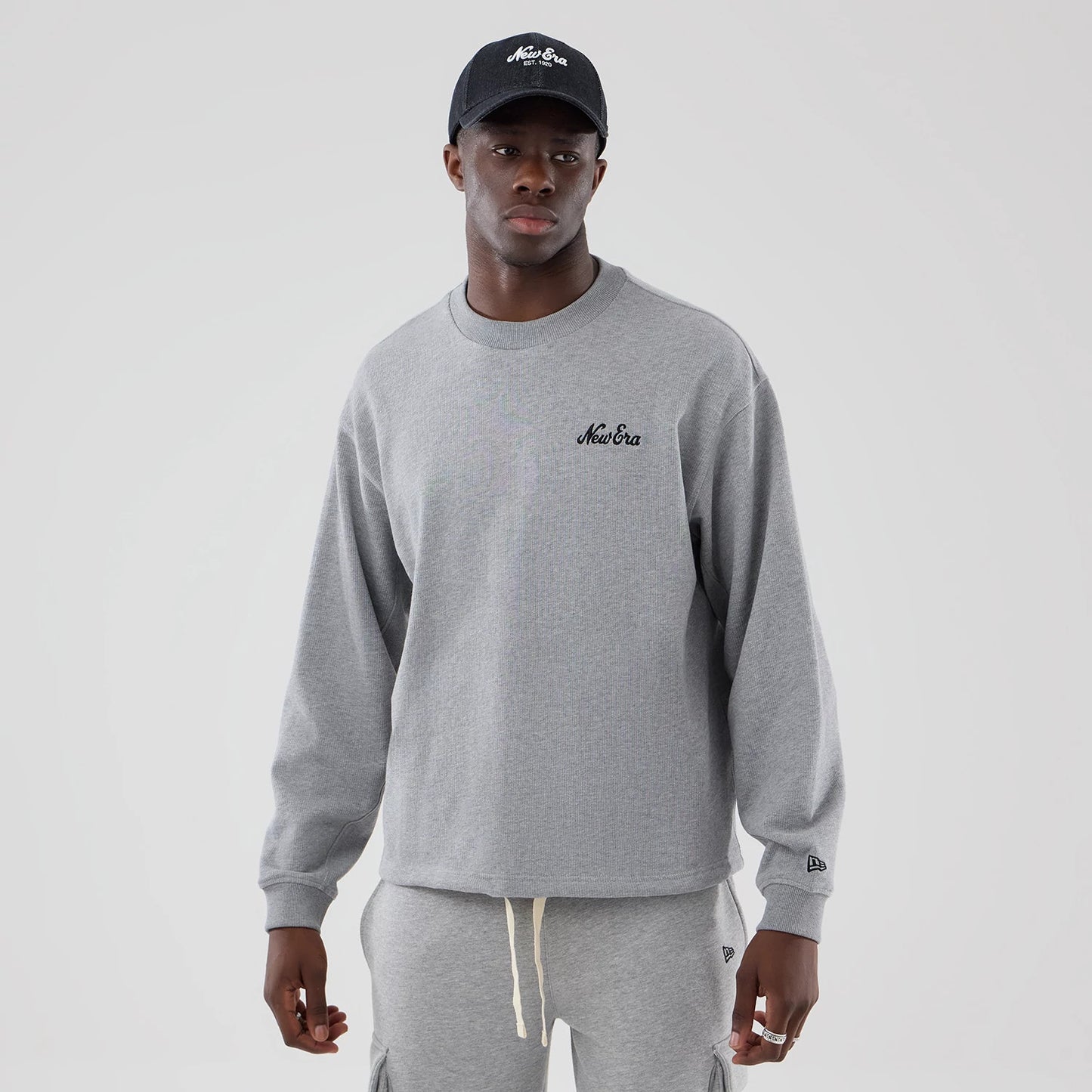 The model is wearing this New Era Oversized Crew Neck Sweater in grey. 1