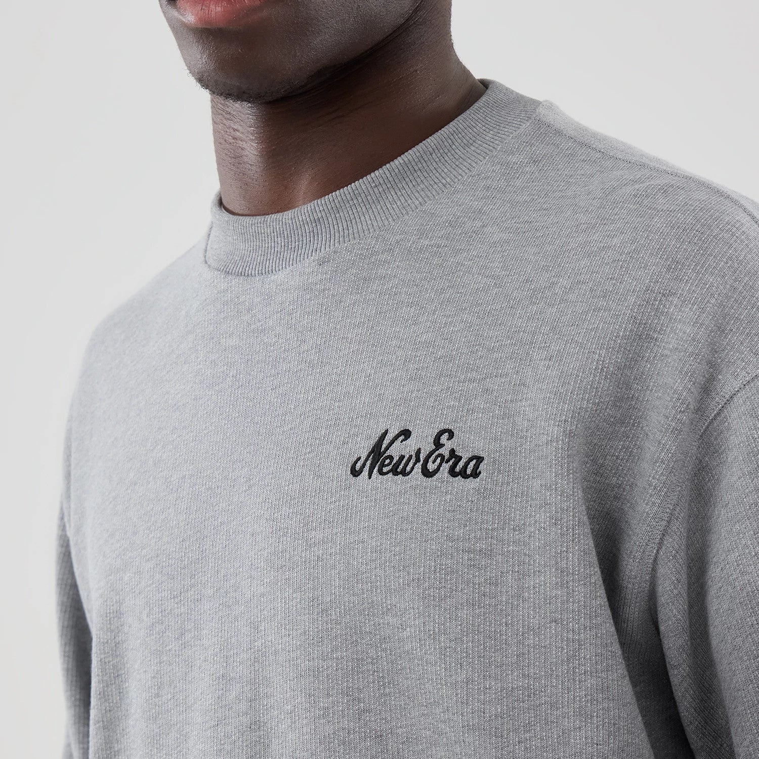 The model is wearing this New Era Oversized Crew Neck Sweater in grey. 4