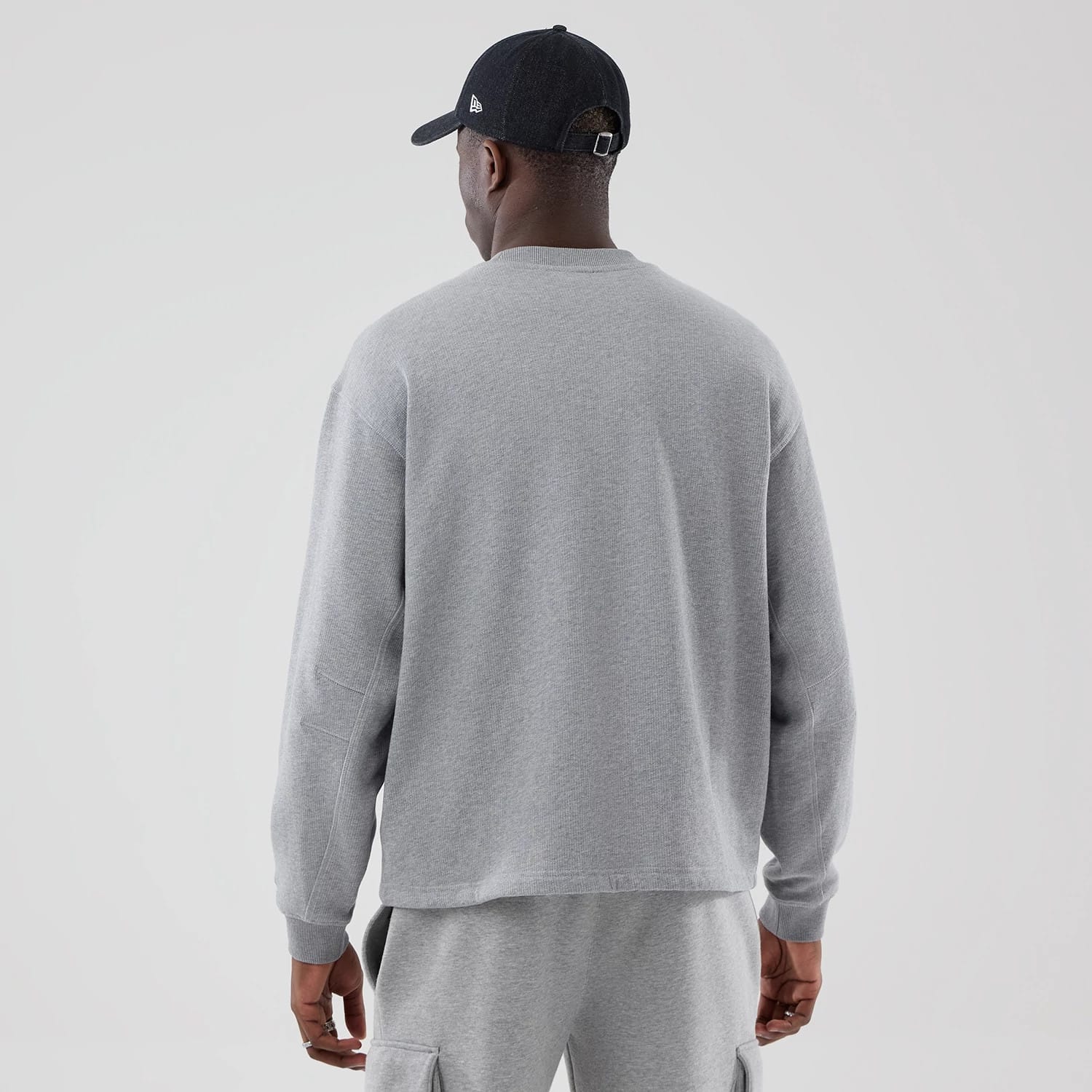 The model is wearing this New Era Oversized Crew Neck Sweater in grey. 2