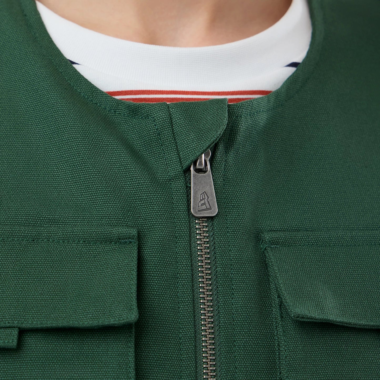 The model is wearing this New Era Utility Vest in dark green. 6
