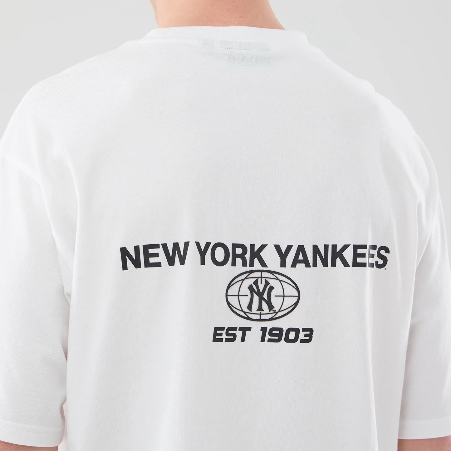 The model is wearing this MLB Logo Graphic New York Yankees Oversized T-Shirt in white. 7
