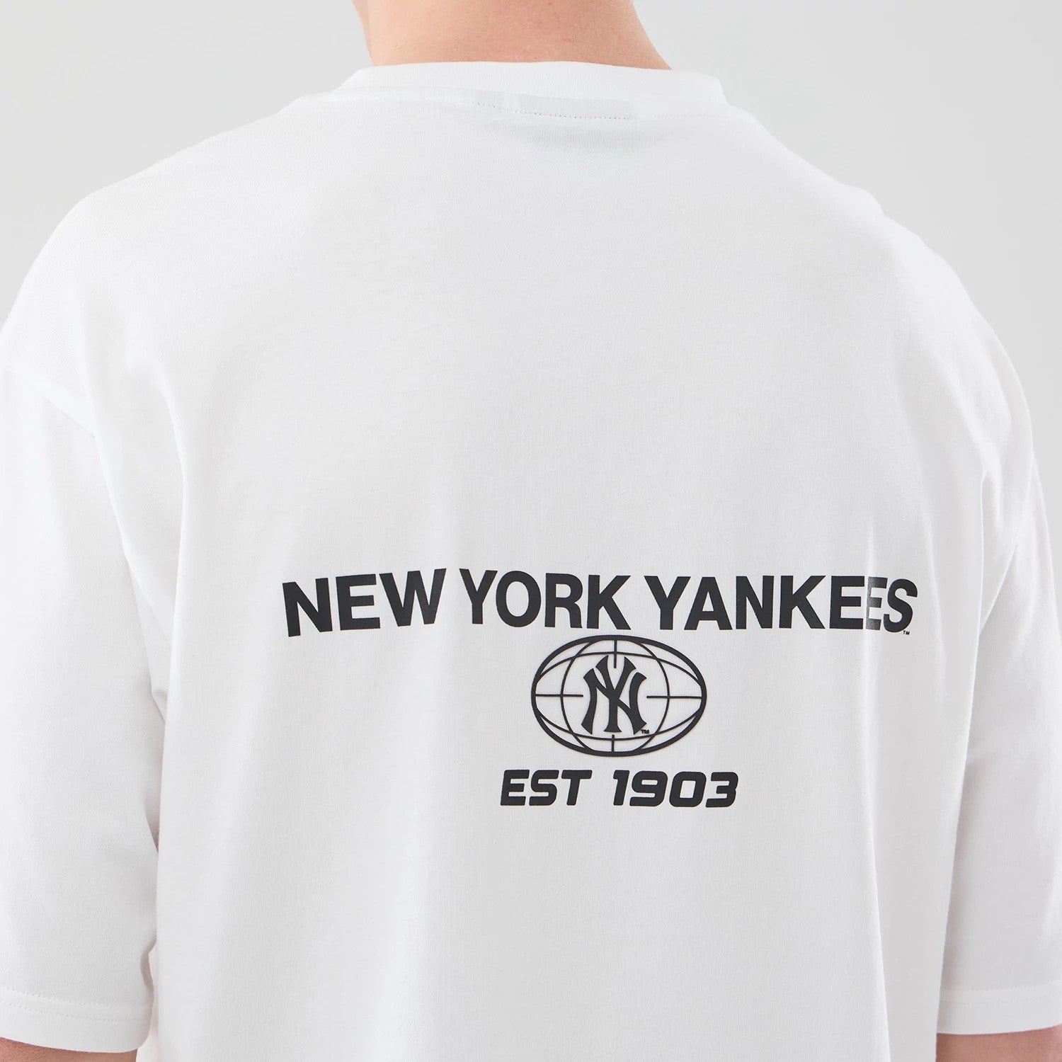 The model is wearing this MLB Logo Graphic New York Yankees Oversized T-Shirt in white. 7
