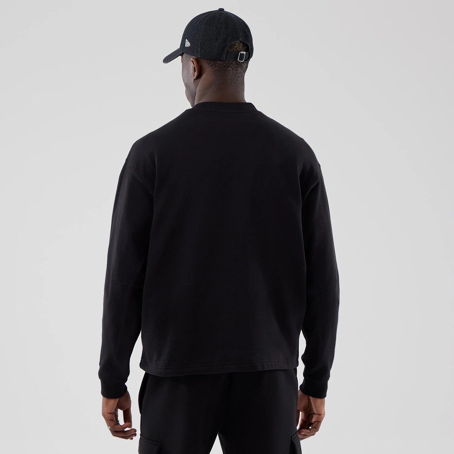 The model is wearing this New Era Oversized Crew Neck Sweater in black. 2