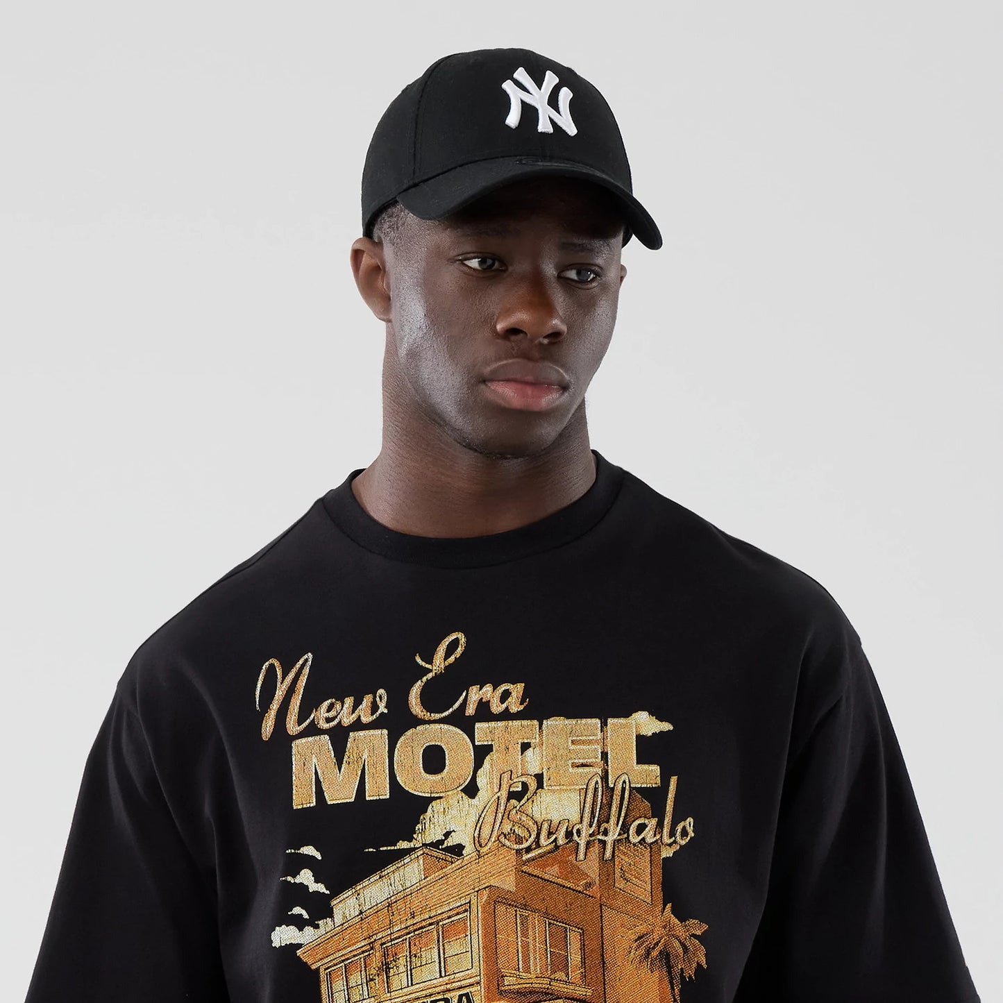 The model is wearing this New Era Motor Graphic Oversized T-Shirt in black. 6