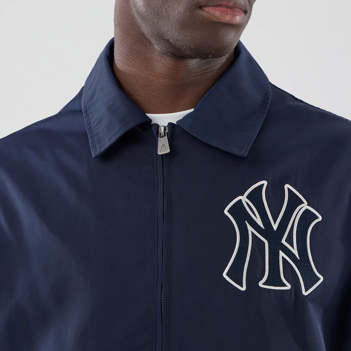 New Era New York Yankees MLB Collared Navy Jacket, front view showing a large white embroidered Yankees logo on the left chest, a pointed collar, and a central zip closure partially under the collar with a small branded pull tab.