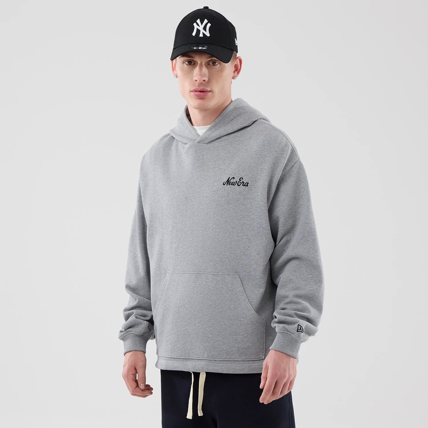 The model is wearing this New Era Open Hem Pullover Hoodie in grey. 1