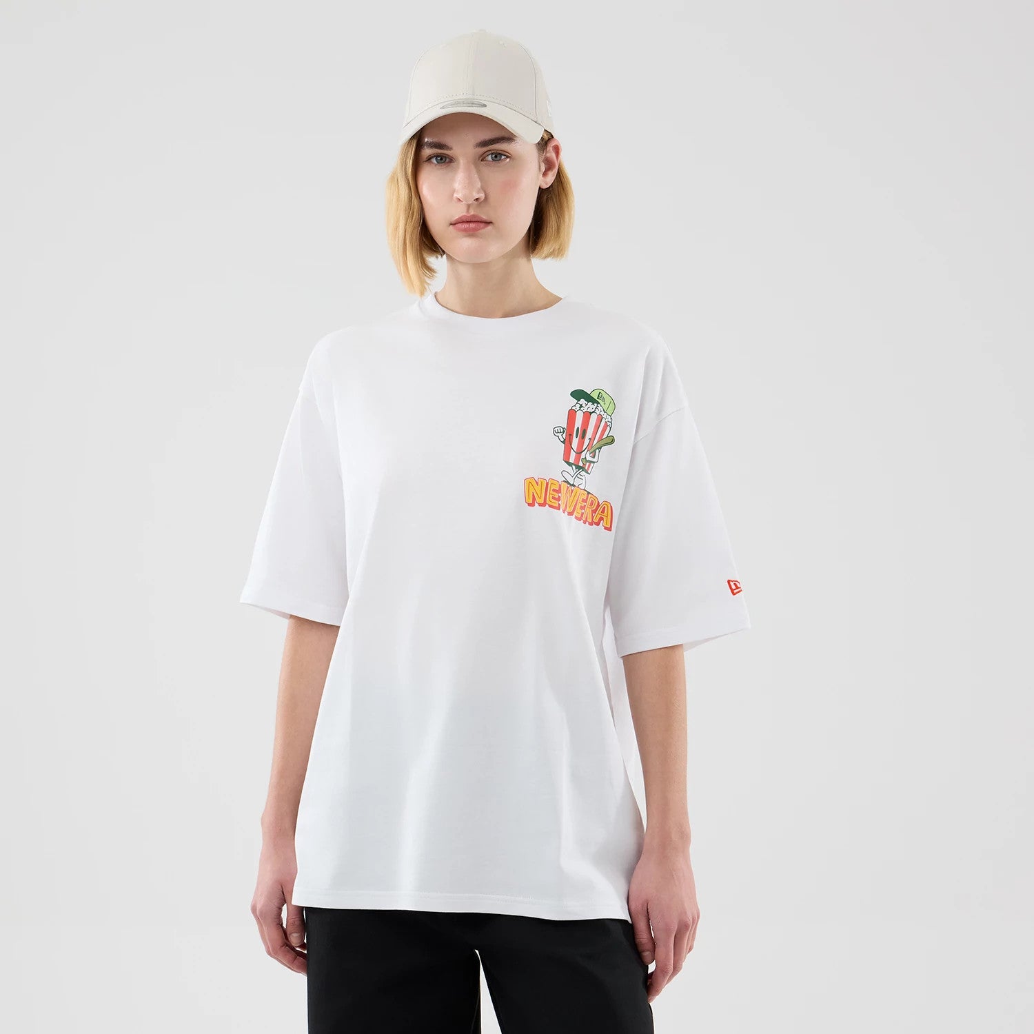 The model is wearing this New Era Baseball Popcorn Graphic Oversized T-Shirt in white. 4