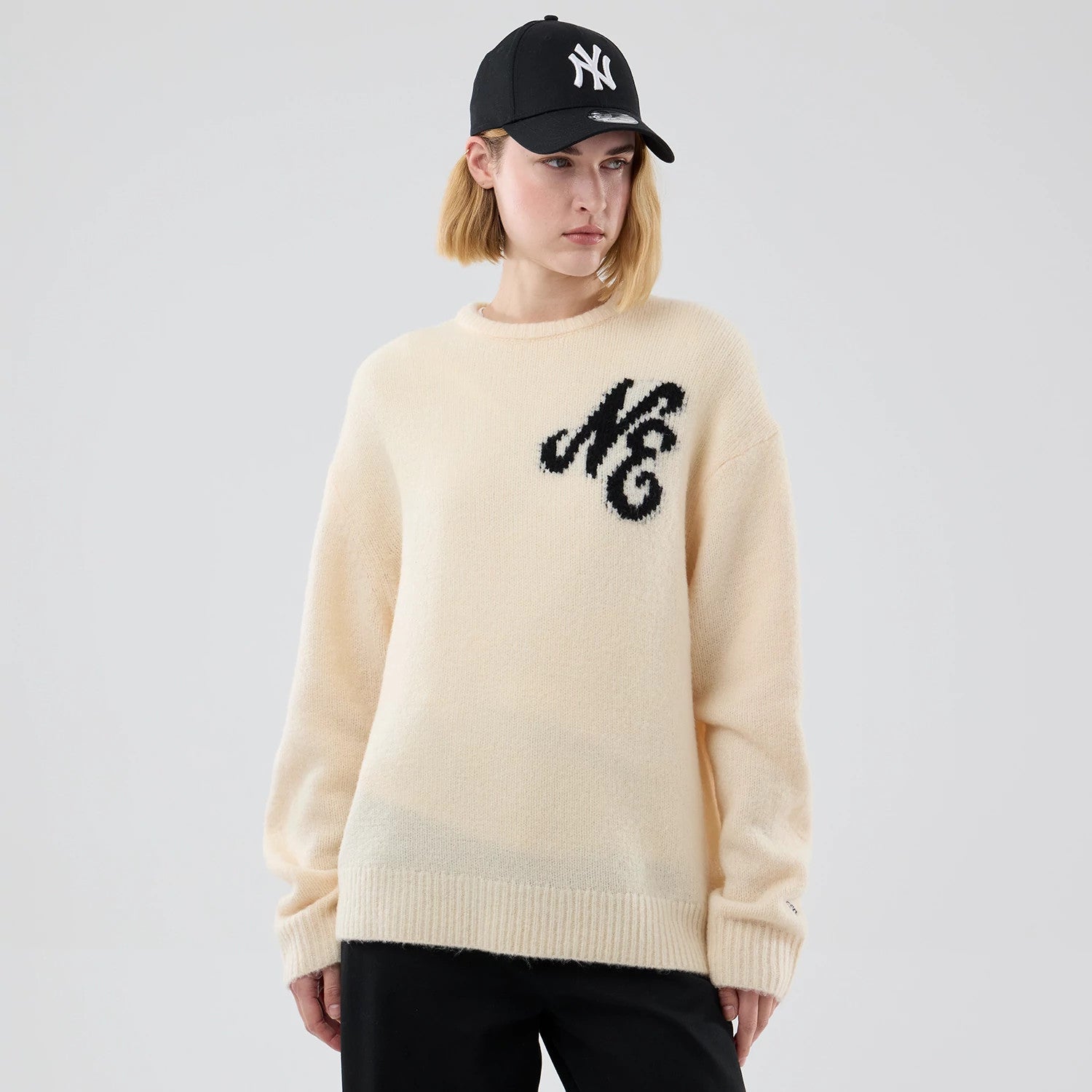 The model is wearing this New Era Knit Knitted Sweater in cream. 4