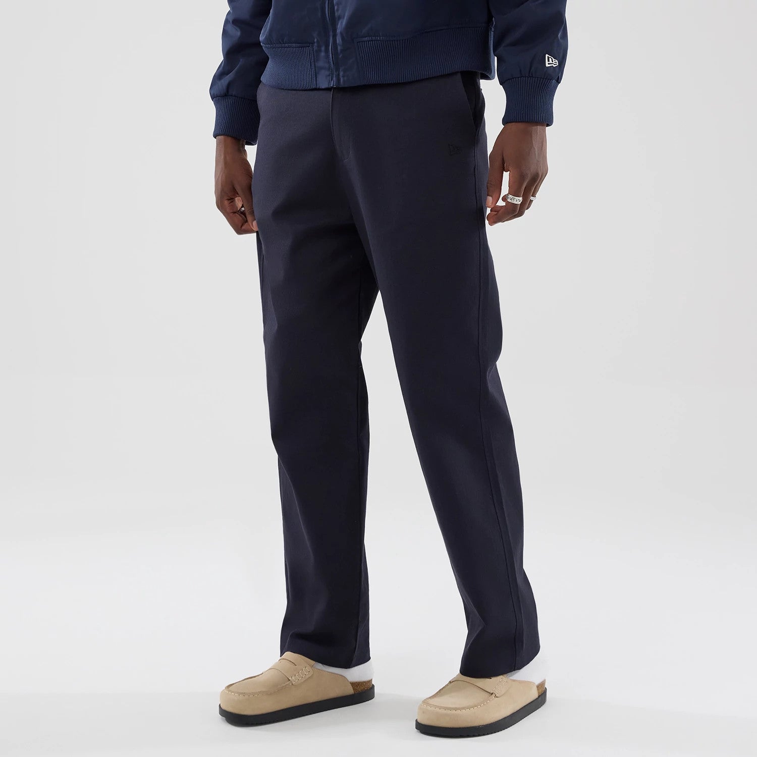 The model is wearing these New Era Chino Trousers in navy. 3