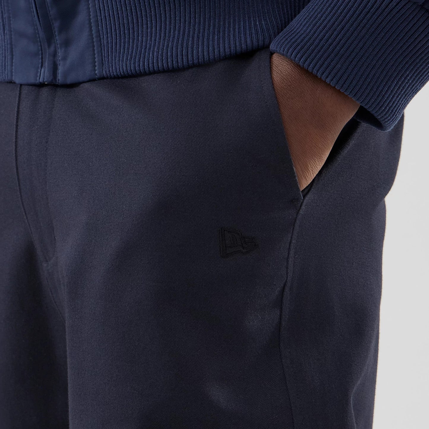 The model is wearing these New Era Chino Trousers in navy. 5