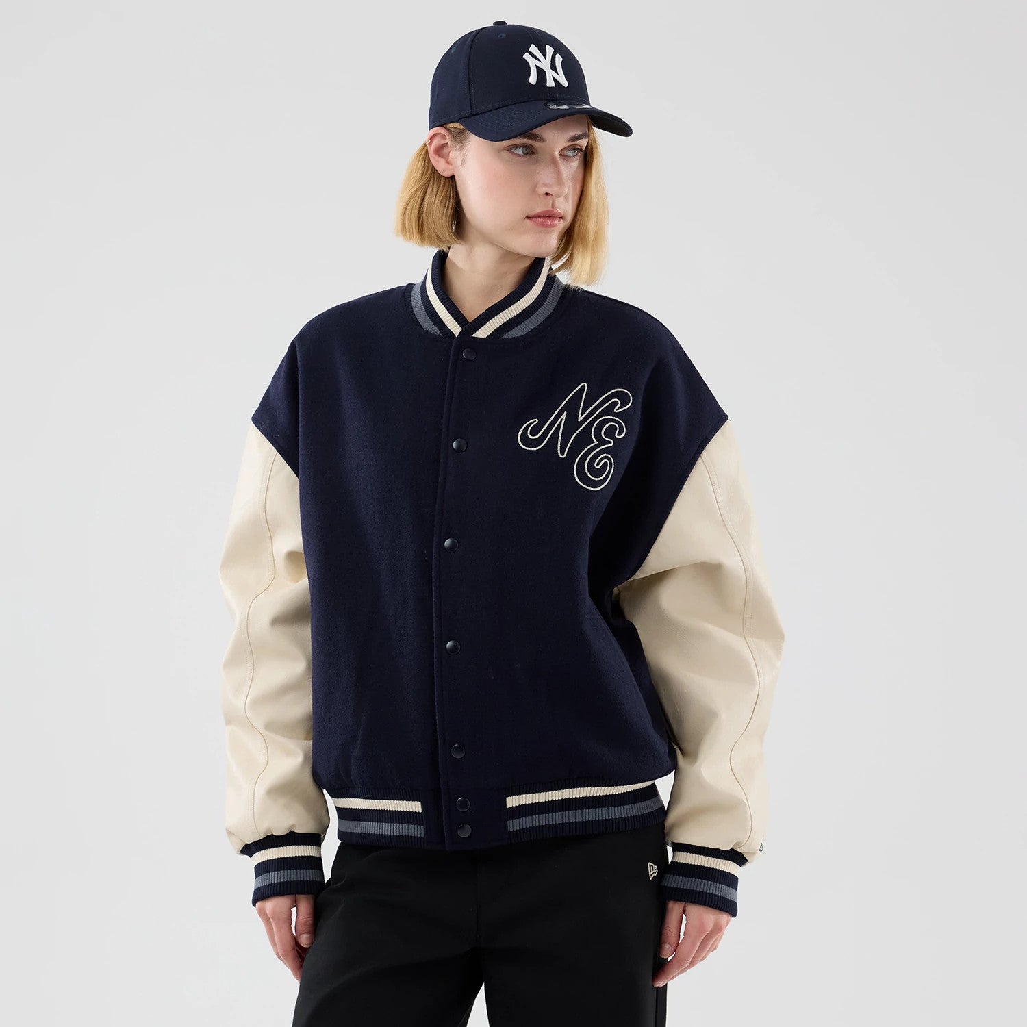 The model is wearing this New Era Oversized Varsity Jacket in navy. 4