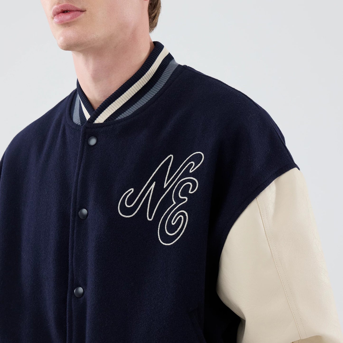 The model is wearing this New Era Oversized Varsity Jacket in navy. 5
