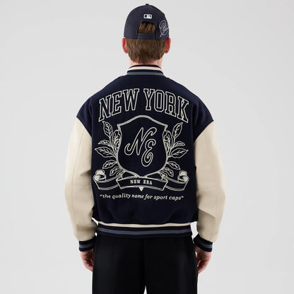 The model is wearing this New Era Oversized Varsity Jacket in navy. 2
