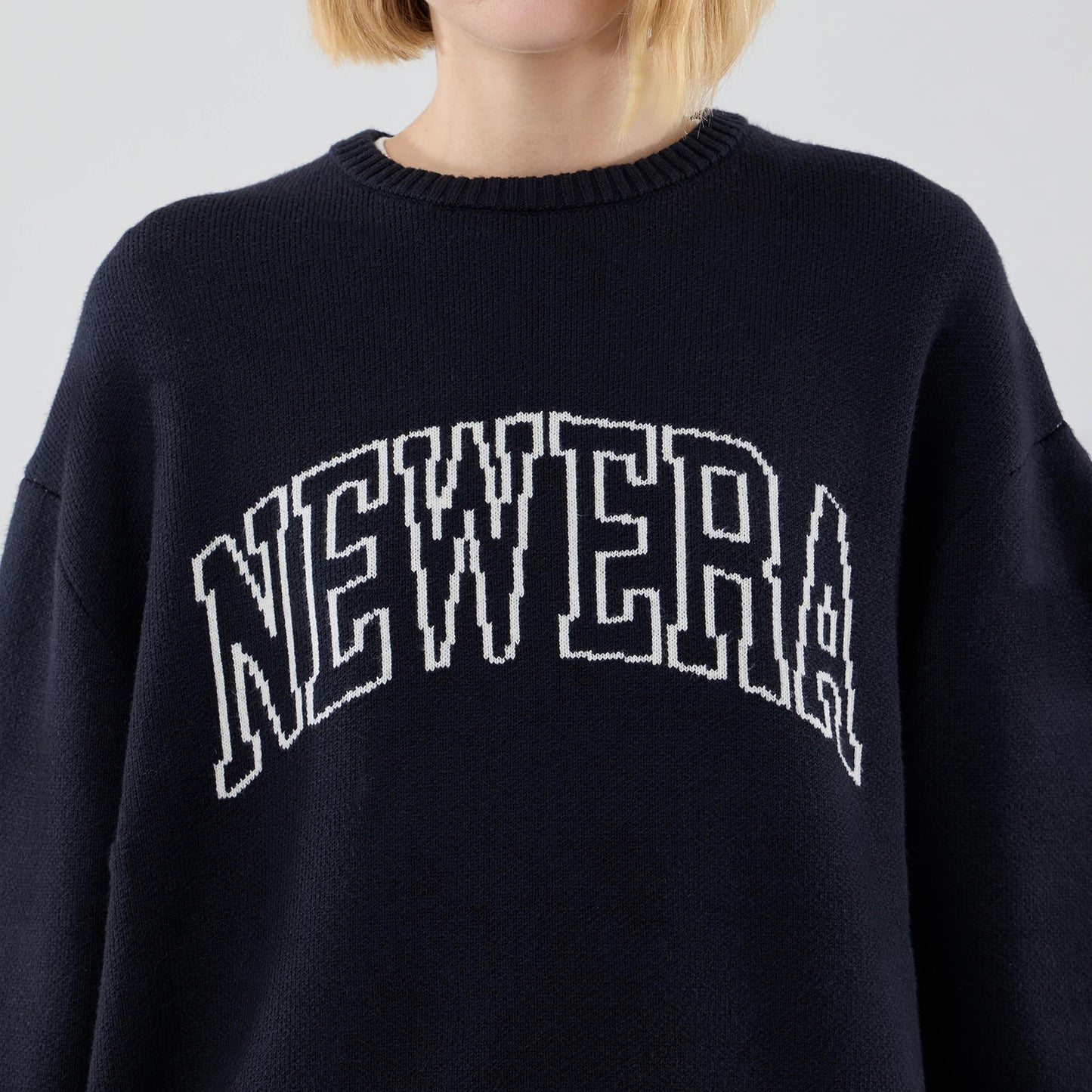 The model is wearing this New Era Knit Script Knitted Sweater in navy. 6