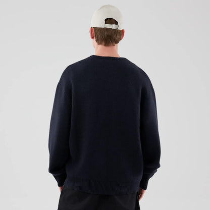 The model is wearing this New Era Knit Script Knitted Sweater in navy. 2