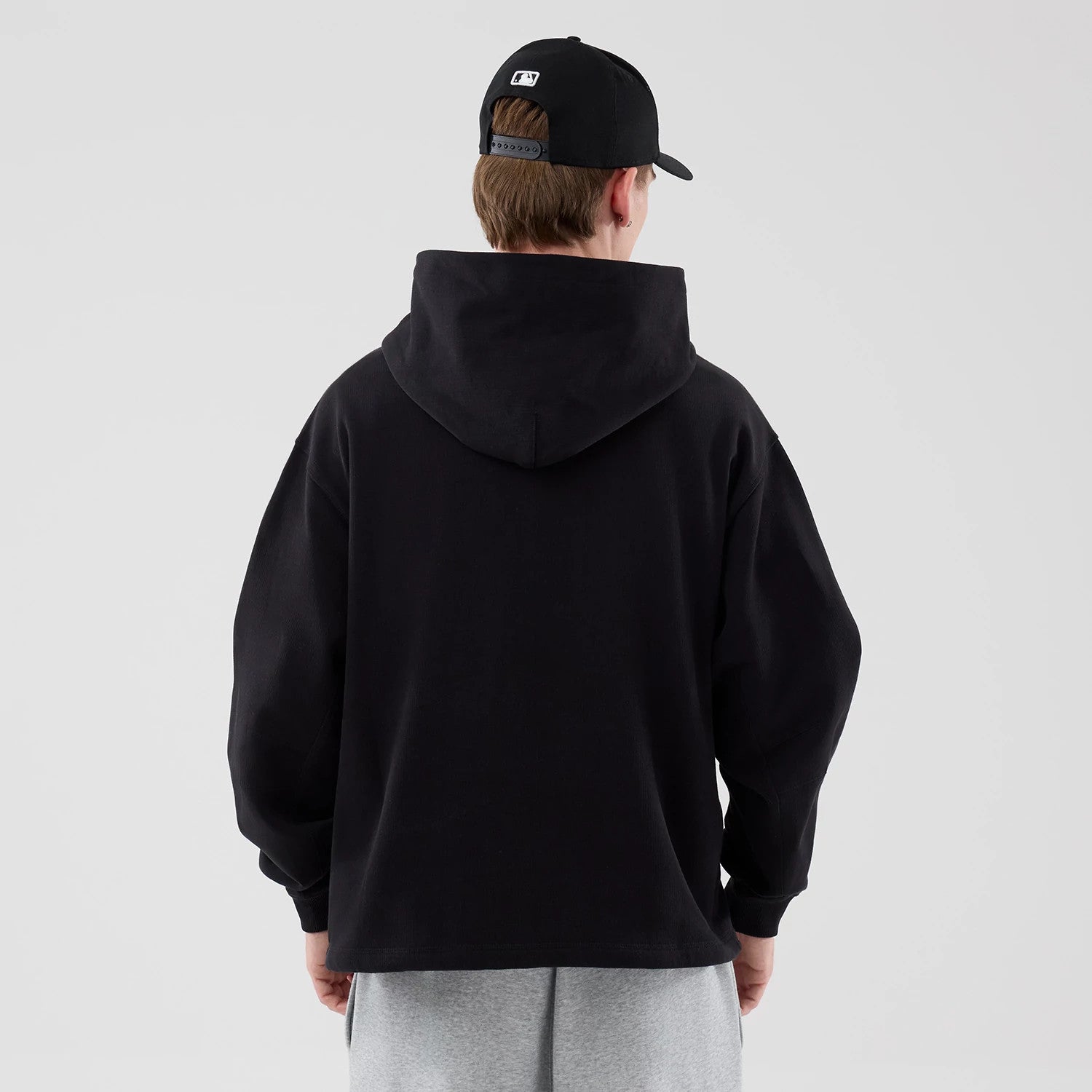 The model is wearing this New Era Open Hem Pullover Hoodie in black. 2