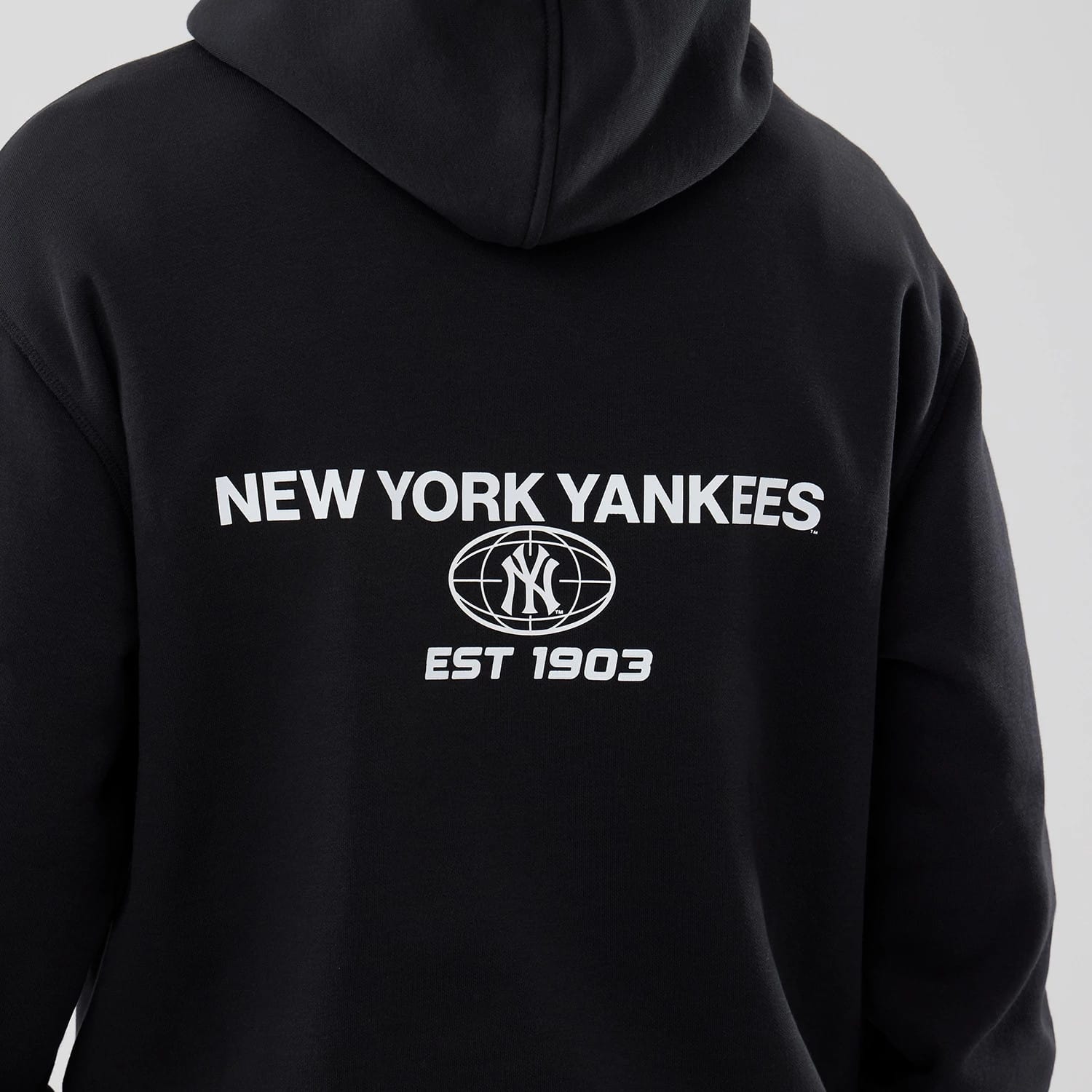 The model is wearing this MLB Logo Graphic New York Yankees Oversized Pullover Hoodie in black. 5
