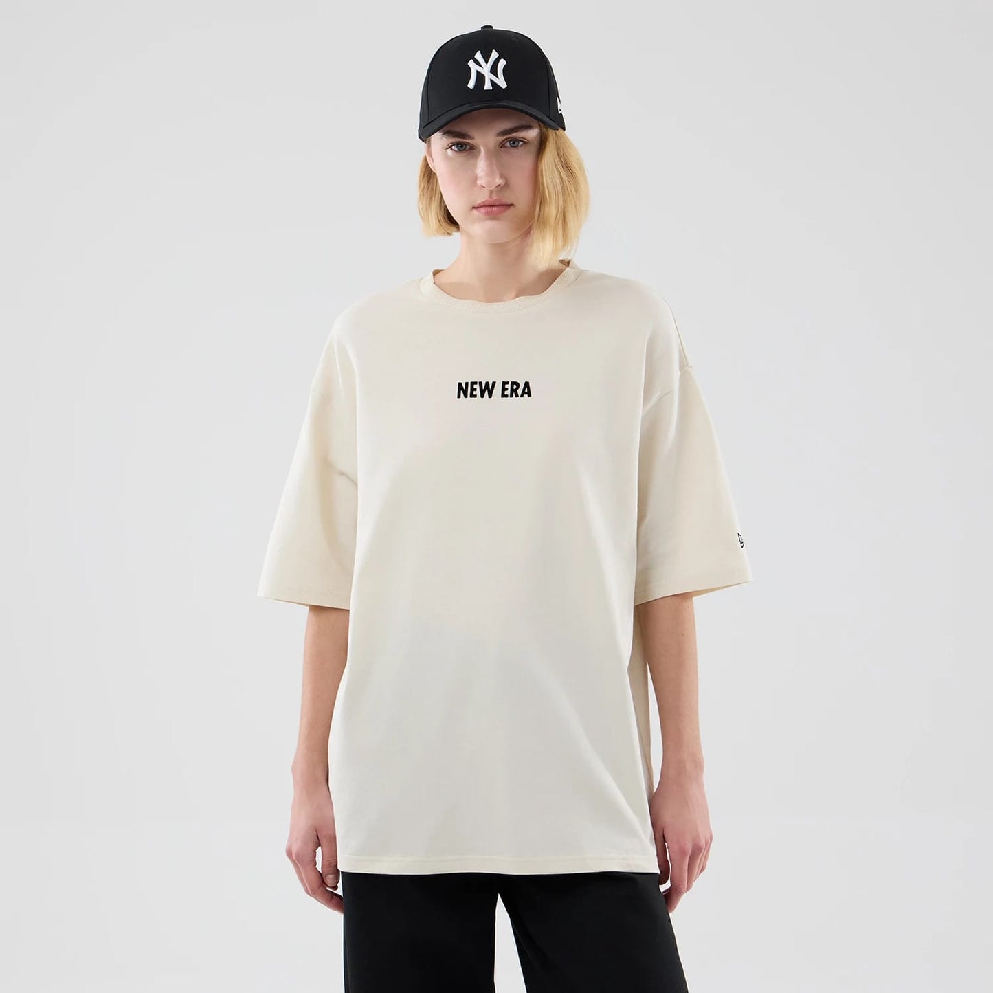 The model is wearing this New Era Cap Graphic Oversized T-Shirt in cream. 4